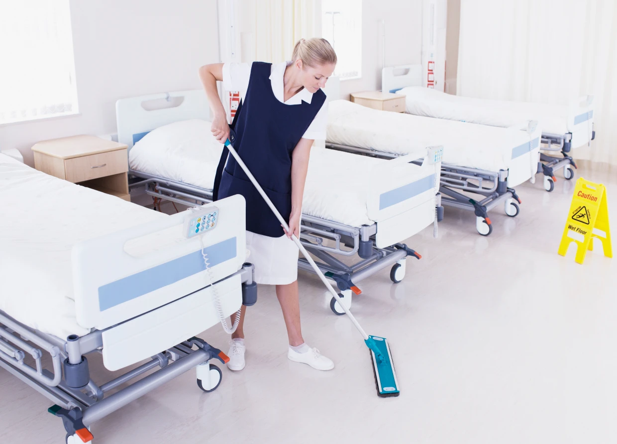 Janitor cleaning between hospital beds